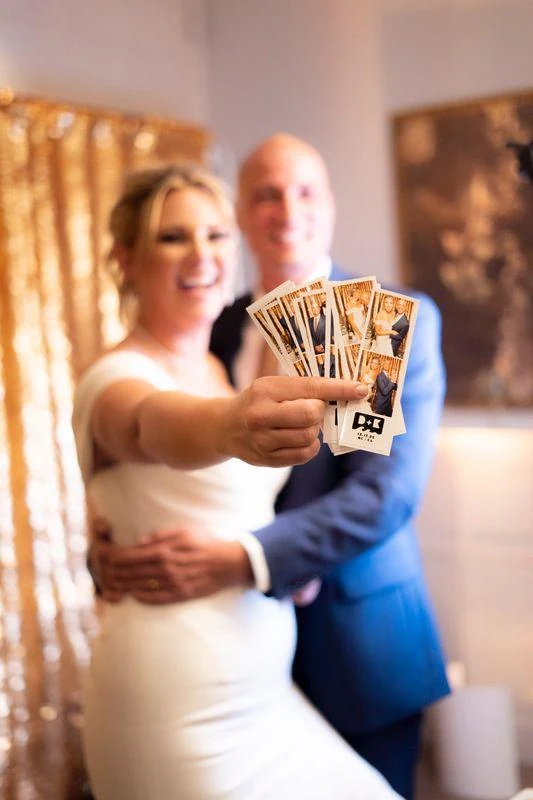 Couple presenting photo strips toward the camera, with the prints in focus