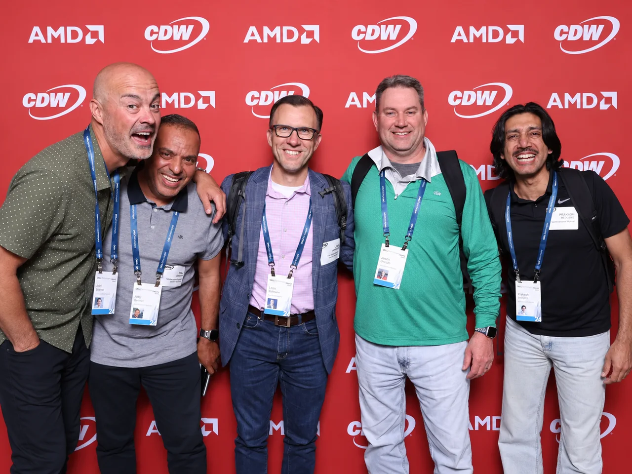Five smiling attendees wearing conference lanyards and badges, arm in arm in front of an AMD and CDW logo wall