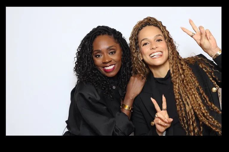 Two guests smiling and making peace signs against a white backdrop