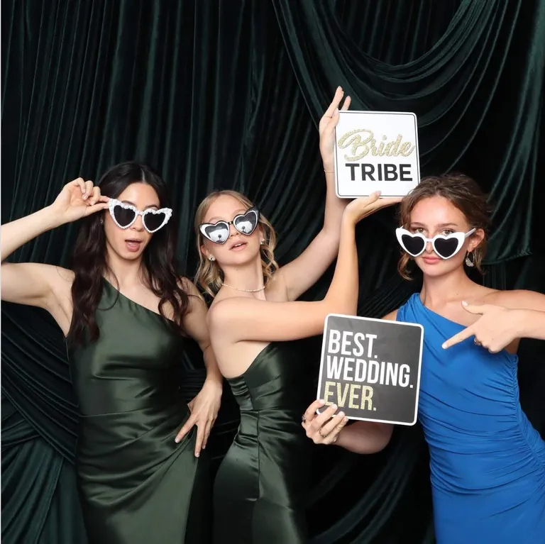 Three wedding guests in heart-shaped sunglasses holding Bride Tribe and Best Wedding Ever signs