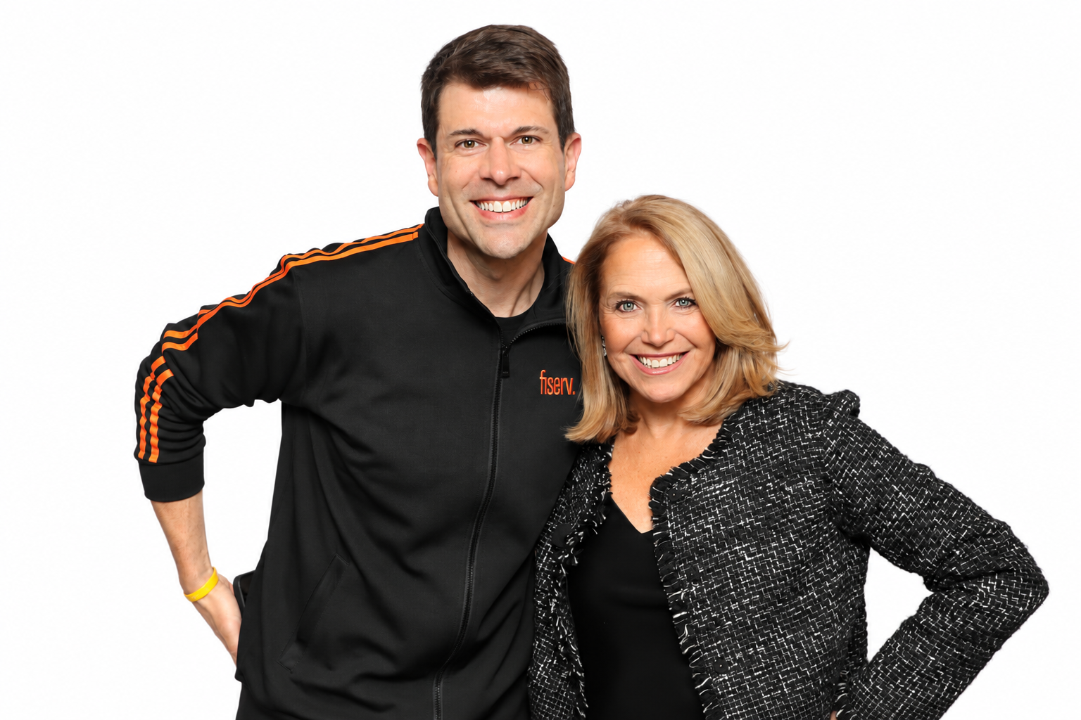 A man in a black track jacket with orange stripes and a woman smiling together against a white background