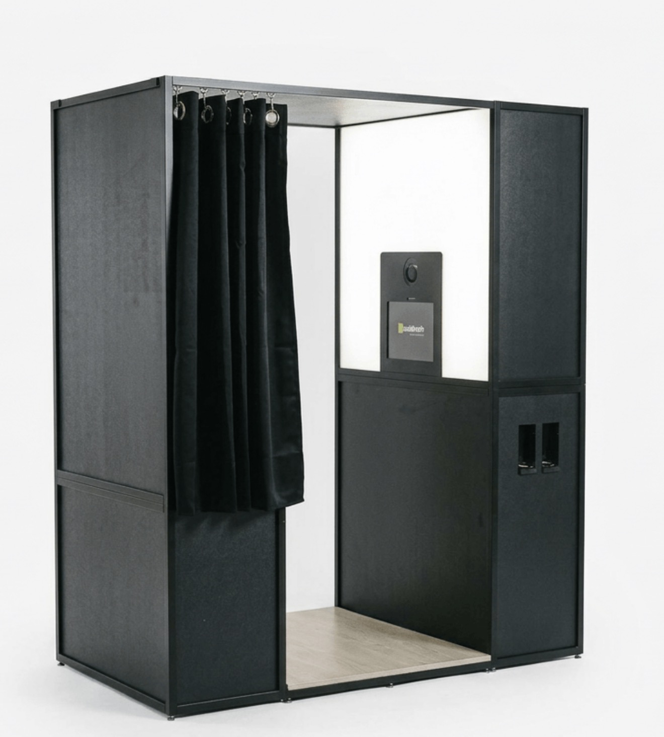 Black enclosed photo booth with an open curtain and interior seat